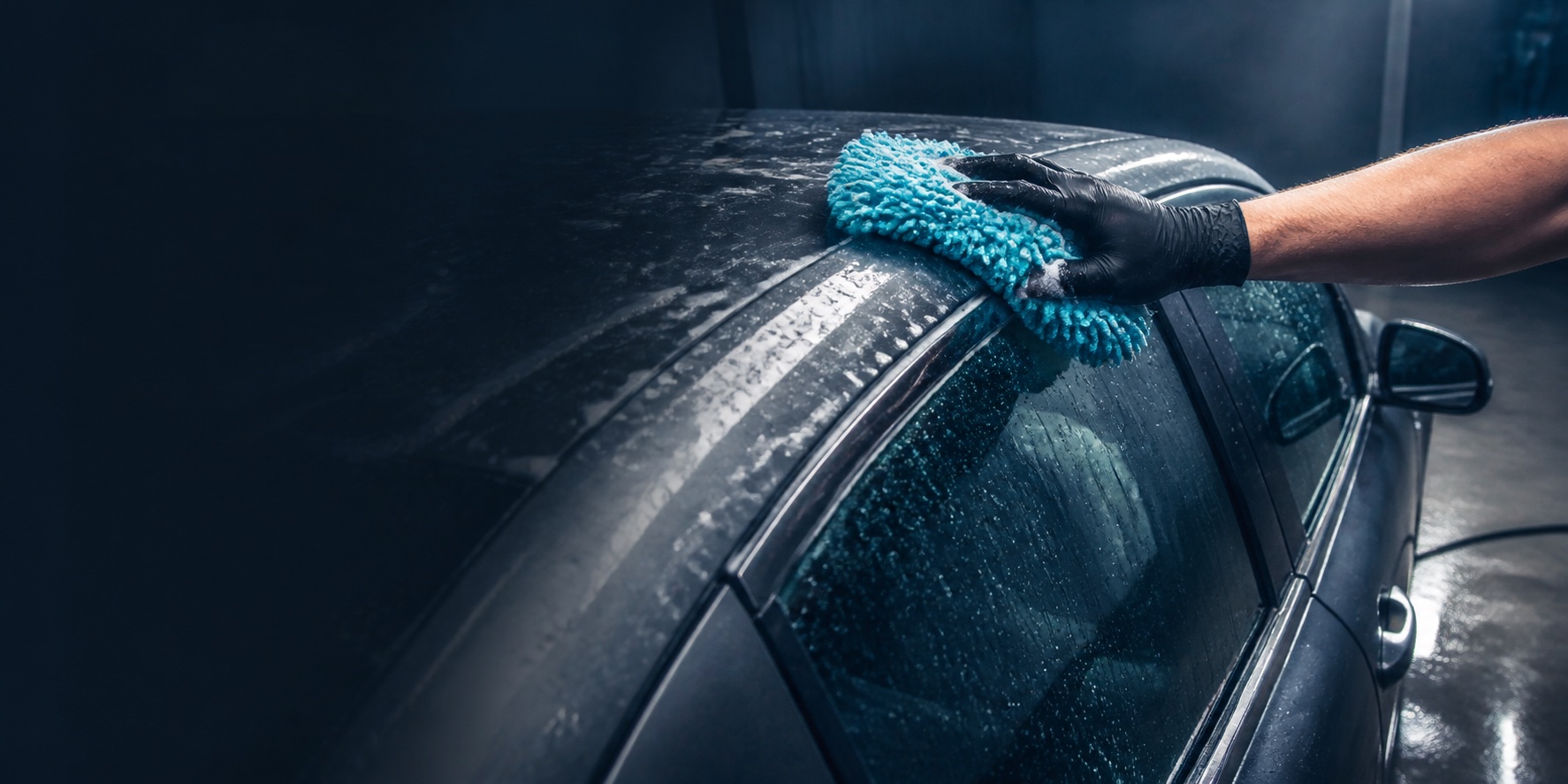 Concept image of a gloved hand using an aqua wash mitt on a car roof